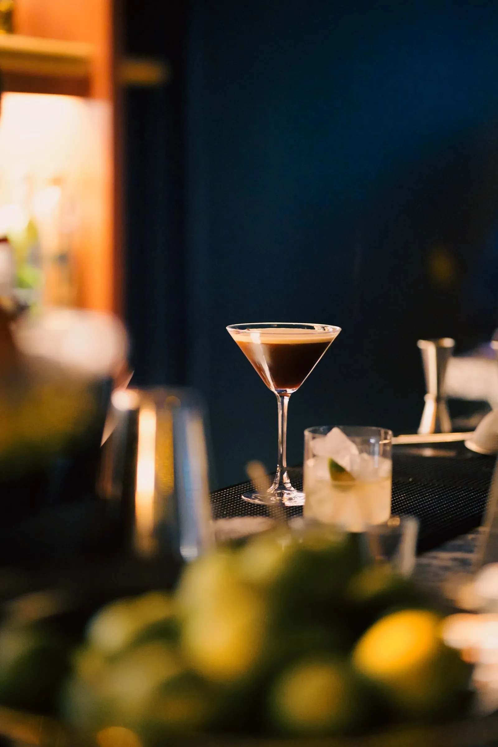 Espresso martini op een bar in blauw kaarslicht met limoenen