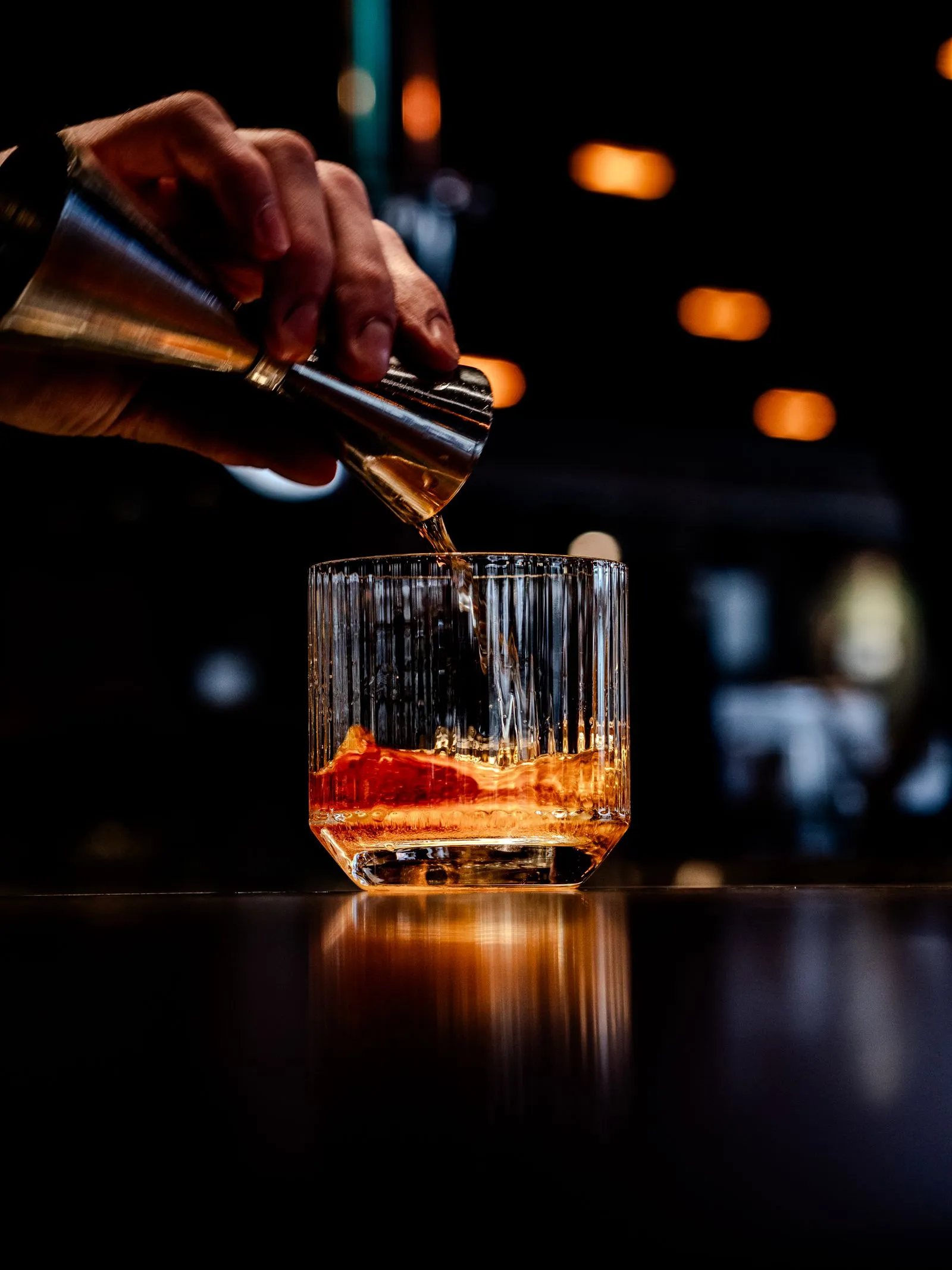 Bartender schenkt een cocktail uit een shaker in een glas met ijs