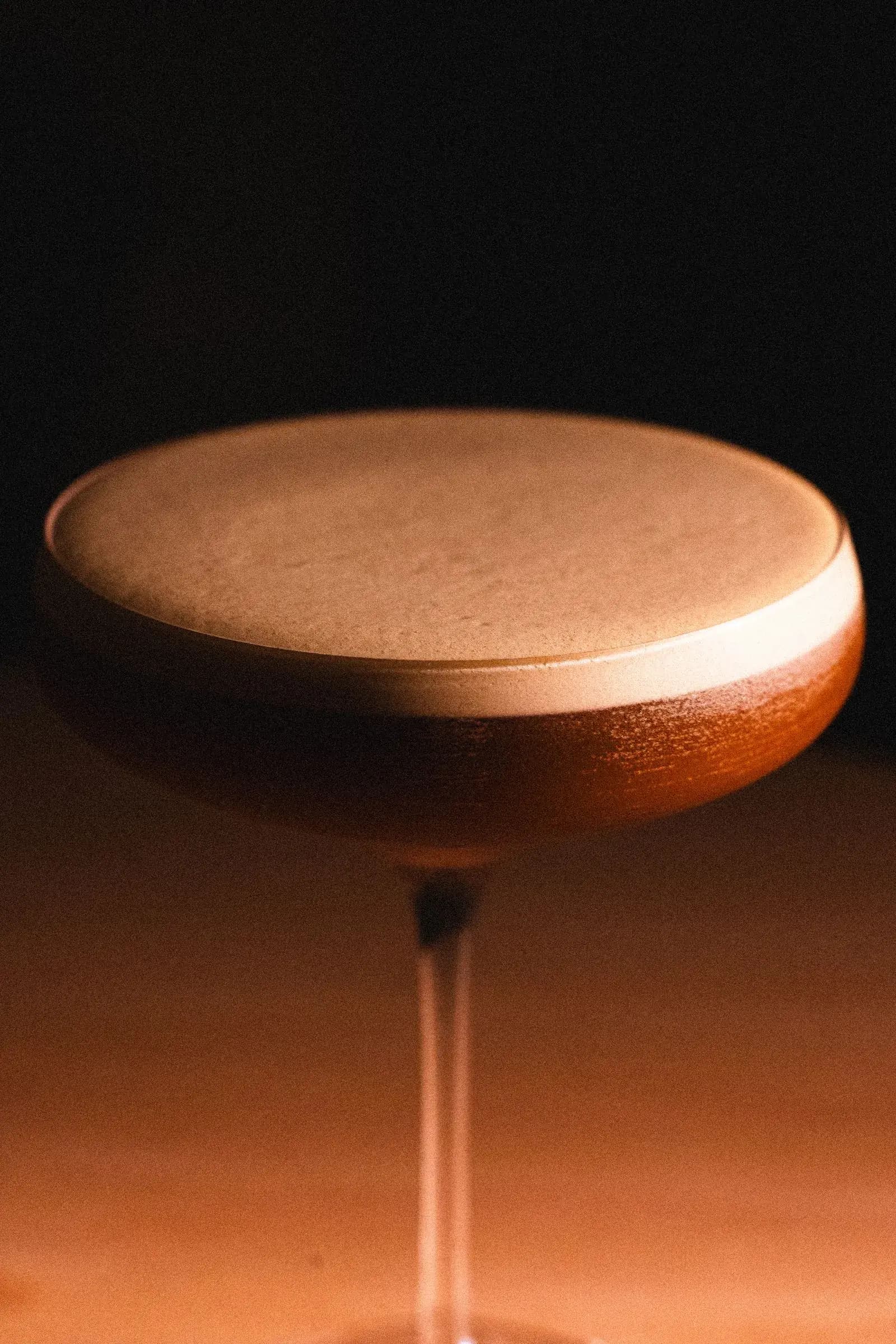 Cocktail met schuimlaag in coupeglas in warm licht