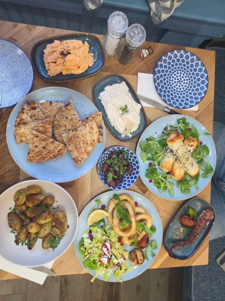 Tafel vol Griekse gerechten om te delen: pita, halloumi-salade, calamares en dips