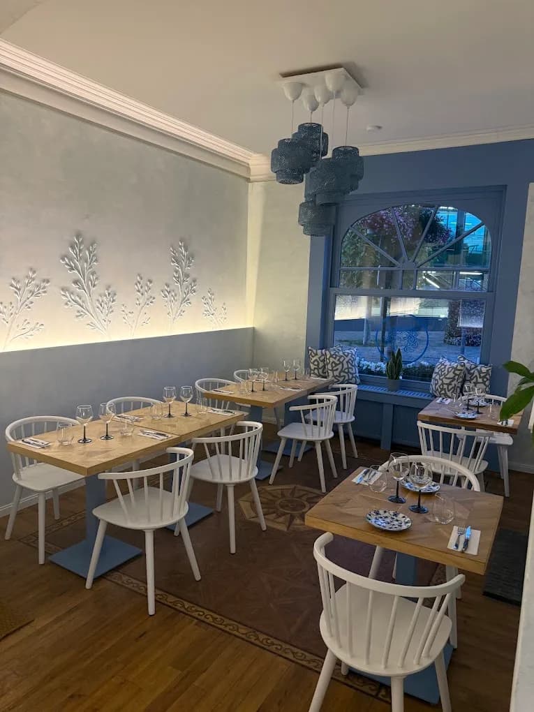 Voorste zaal met groot raam, witte stoelen en blauw tegelpad